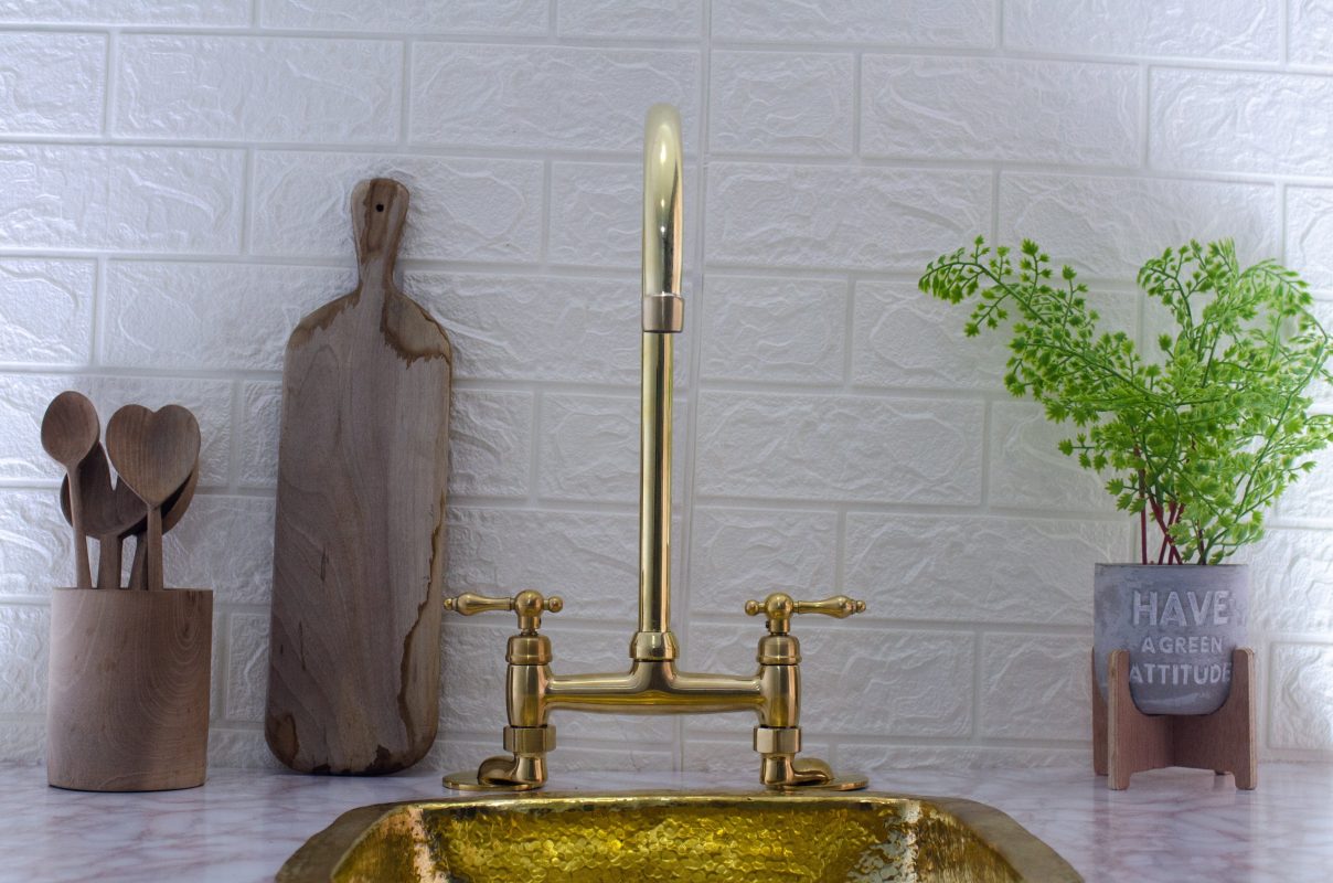 Antique Brass Bridge Faucet - A stunning brass bridge kitchen faucet with an antique brass finish. This vintage-inspired faucet exudes elegance and adds a touch of timeless charm to your kitchen. The bridge design features two handles and a swiveling spout, offering both functionality and beauty. The solid brass construction ensures durability and longevity, making it a lasting addition to your kitchen. Experience the allure of vintage design with this antique brass bridge faucet.